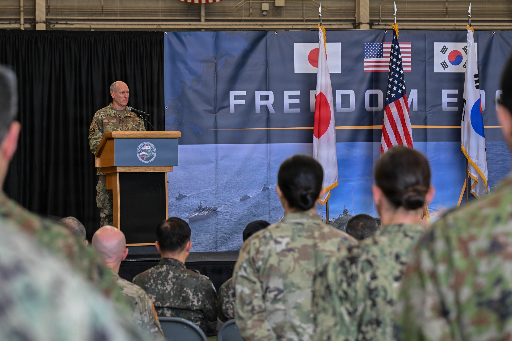 Lt. Gen. Stephen Jost addresses U.S., Japanese, and South Korean service members at the Freedom Edge 2026 opening ceremony at Yokota Air Base